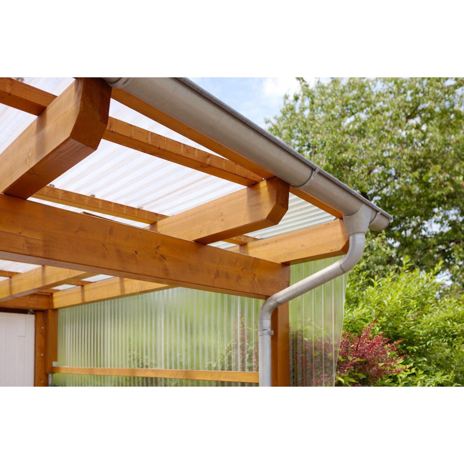 Transparente Acryl-Trapezplatte als Bedachung für eine Holzkonstruktion mit Regenrinne.