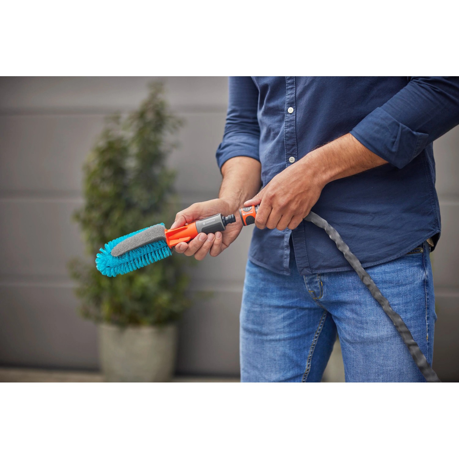 Gardena Cleansystem Fahrradbürste in Blau mit Gartenschlauchanschluss in der Hand.