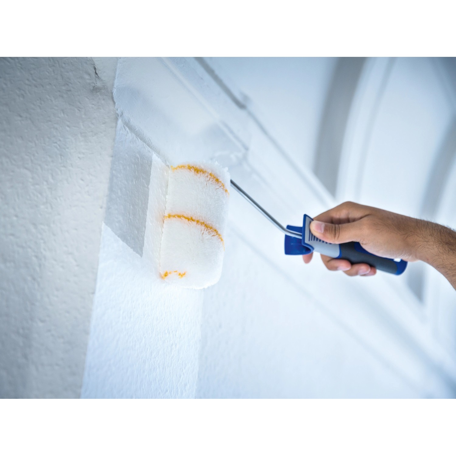 LUX Dispersionsroller 15 cm im Einsatz: Hand streicht weiße Wand mit Farbwalze.