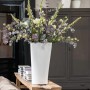Weiße Lechuza Delta Premium Pflanzsäule (40x40x75cm) mit Blumenarrangement.