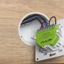Grüner Shelly Smarte Relais Dimmer Gen 4 für Hausautomation, installiert in einer Wanddose.