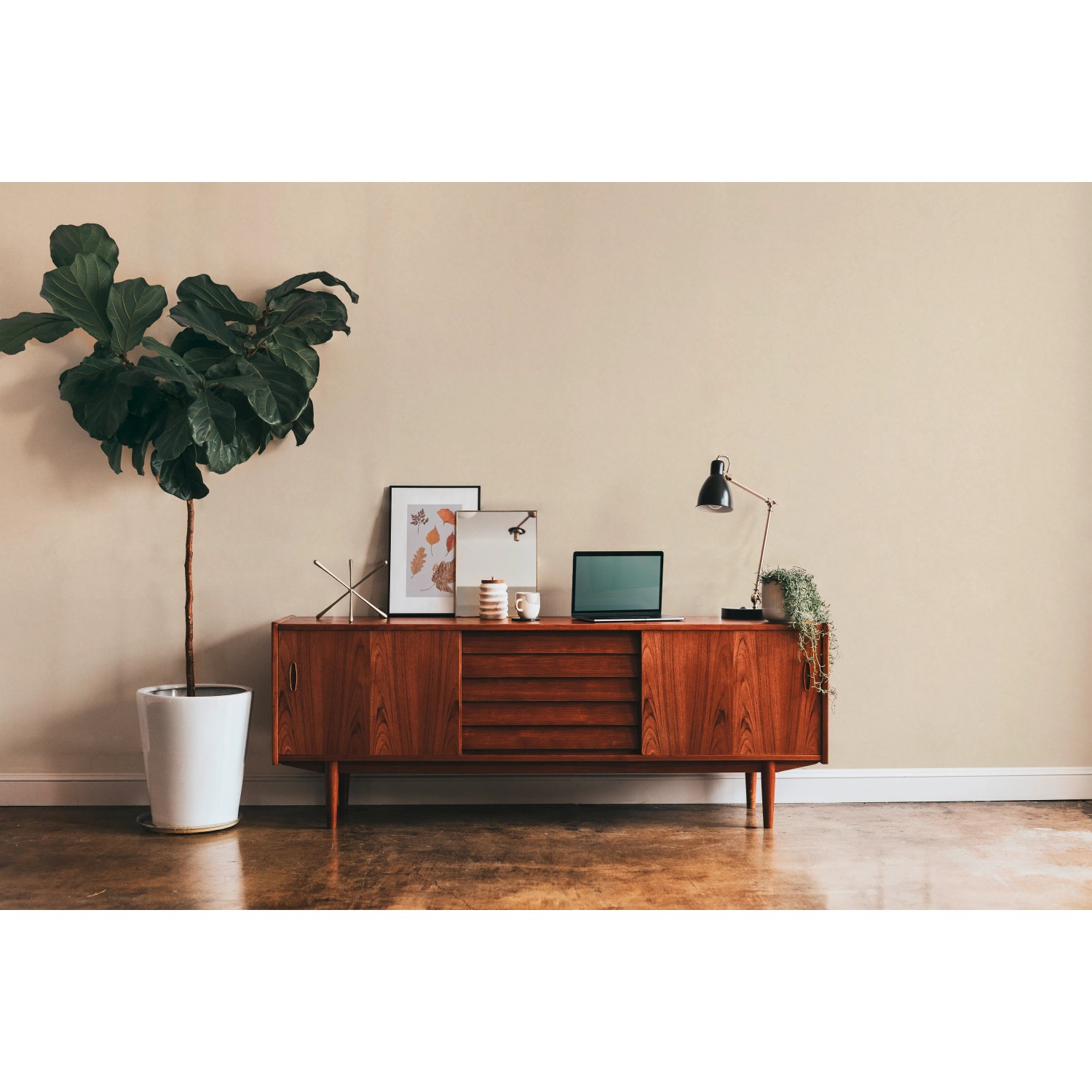 Beige Uni-Vliestapete „Metropolitan Stories II“ an Wand hinter Sideboard im Wohnraum.