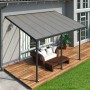 Anthrazit Terrassenüberdachung Feria 3x4.25 von Palram-Canopia mit Möbeln auf Holzterrasse.