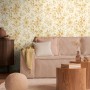 AS Creation Vliestapete Blüten in Weiß-Gold an Wohnzimmerwand mit Couch und Deko.