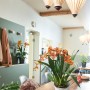 Lechuza Orchidea Color, weißes Pflanzgefäß mit orangefarbener Orchidee auf Holztisch.