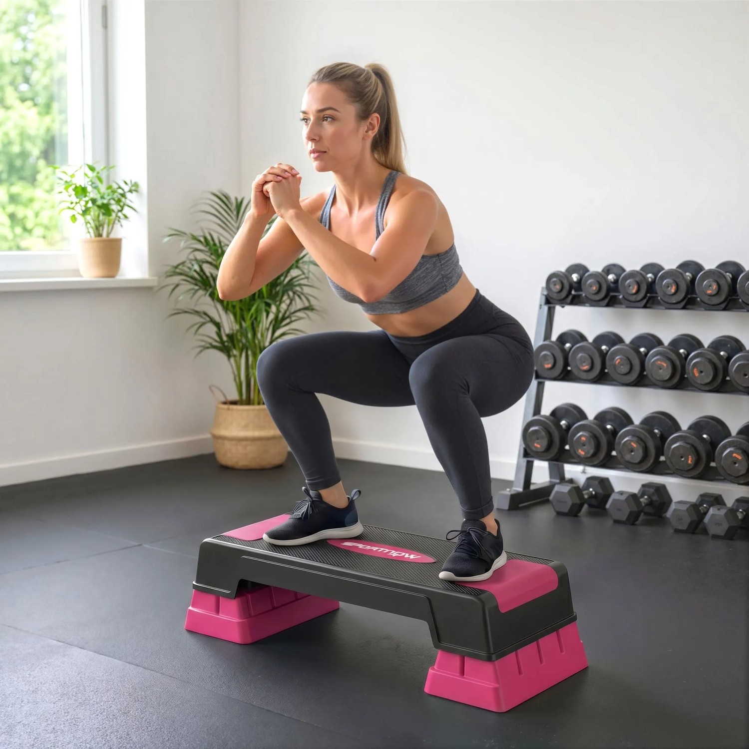 Frau macht Kniebeugen auf rosa-schwarzem, höhenverstellbarem Aerobic Stepper. Ideal für Fitness & Training zu Hause.