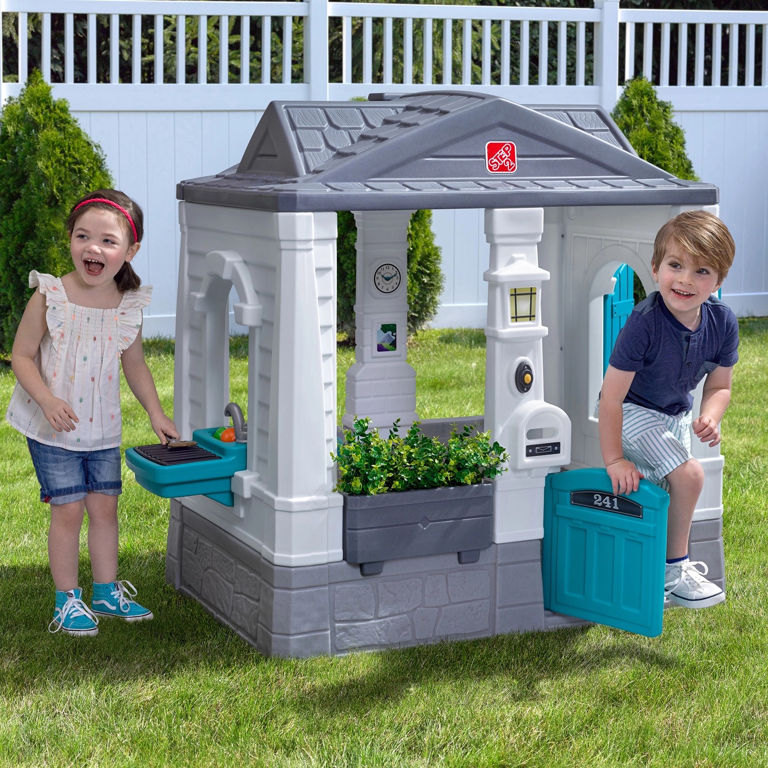 Step2 Spielhaus Neat & Tidy Cottage Homestyle Edition mit Kindern beim Spielen im Garten.