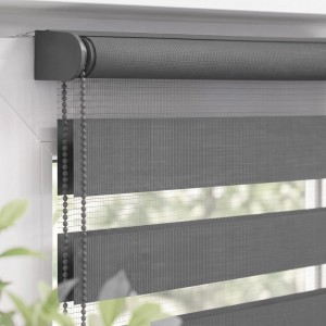 Graues Doppelrollo Klemmfix am Fenster, mit Seitenzug und Tag-Nacht-Funktion für regulierbaren Sichtschutz.