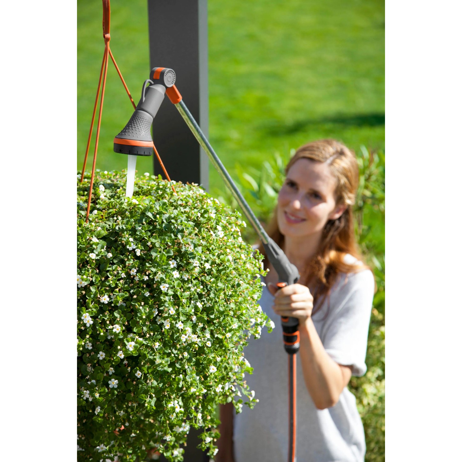 Frau gießt Blumenampel mit Gardena Comfort Gießstab. Gartenspritze mit schwenkbarem Kopf.