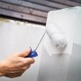 Hand lackiert mit LUX PRO Farbroller Lacke Grau einen Betonpfeiler.