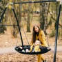 AXI Nestschaukel: Kind liegt in anthrazit-cremefarbener Schaukel mit Metallgestell im Garten.