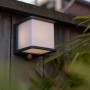 Anthrazitfarbene Lutec LED Solar Wandleuchte Doblo mit Bewegungsmelder an Holzwand.