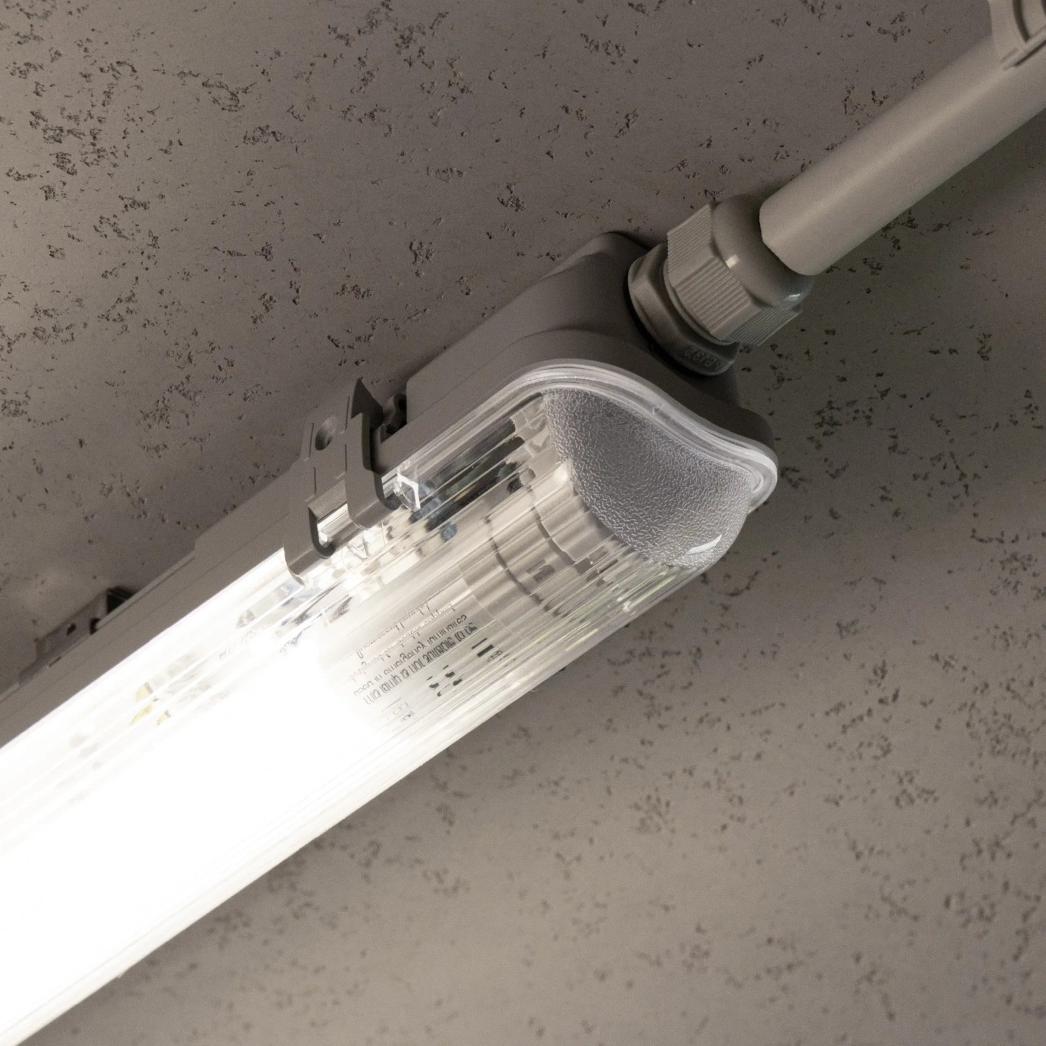Graue LED-Feuchtraumleuchte (17,5 W) mit Rohr an Decke montiert.