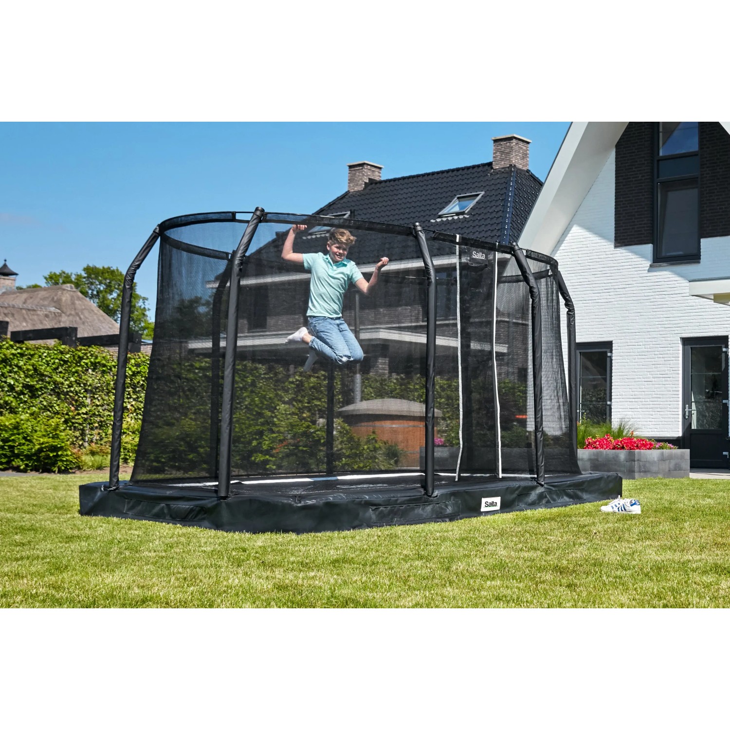Schwarzes Salta Premium Ground Trampolin 305x214 cm mit springendem Kind im Garten.