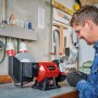 Einhell TC-WD 200/150 Nass-Trockenschleifer in Benutzung, rot/schwarz, mit Mann und Werkstatt im Hintergrund.