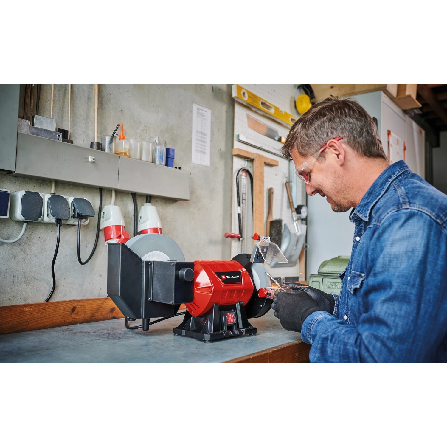 Einhell TC-WD 200/150 Nass-Trockenschleifer in Benutzung, rot/schwarz, mit Mann und Werkstatt im Hintergrund.