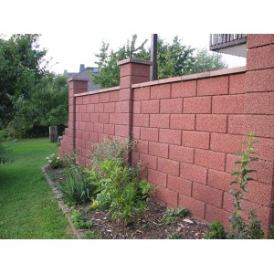 Braune Gartenmauer aus Halbsteinen mit strukturierter Oberfläche als Grundstückseinfassung.