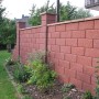Braune Gartenmauer aus Halbsteinen mit strukturierter Oberfläche als Grundstückseinfassung.