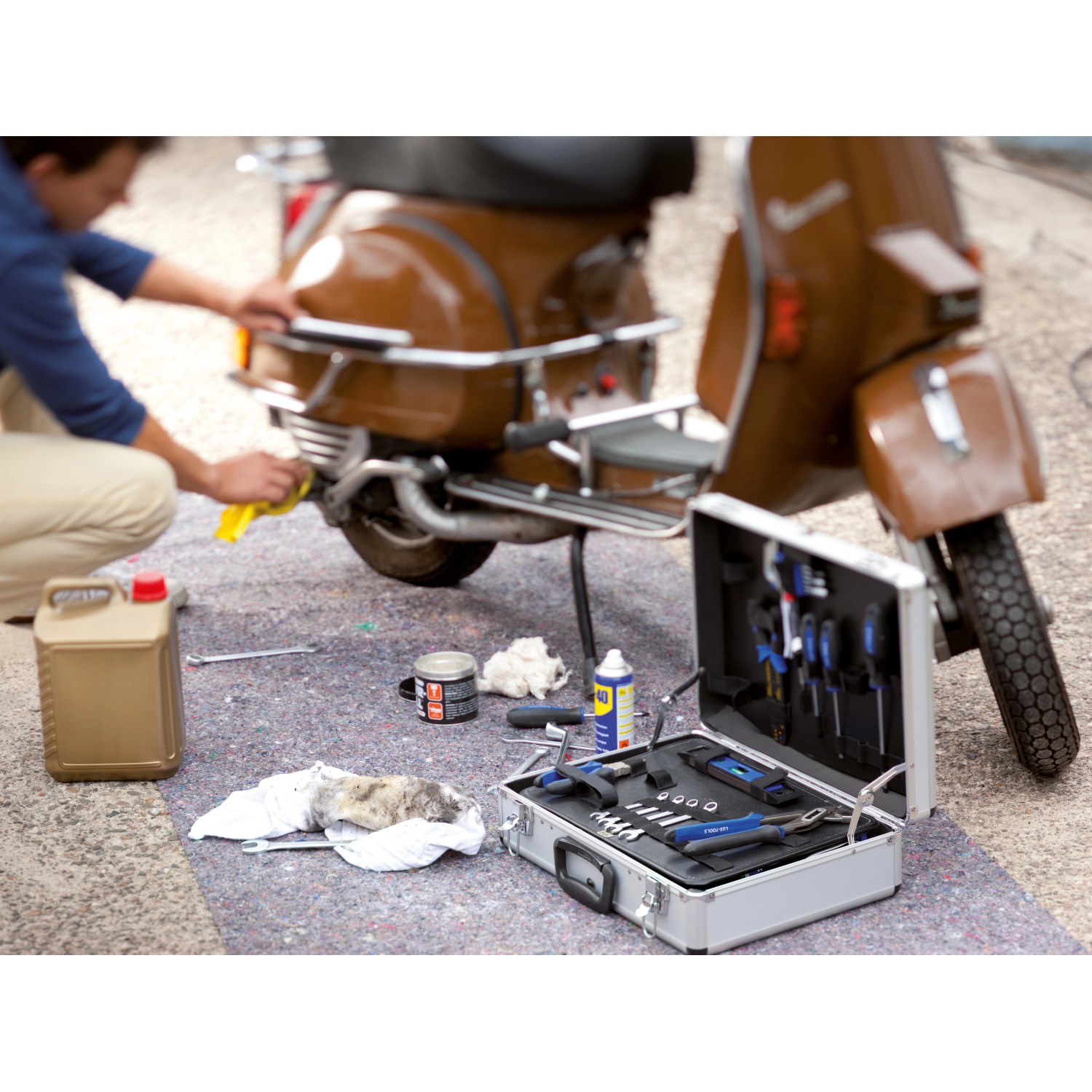 Abdeckvlies schützt Boden bei Reparatur eines Rollers mit Werkzeugkoffer und Zubehör.