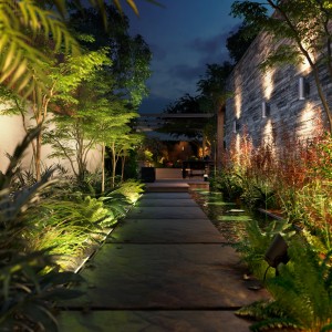 Philips Hue Amarant Wandfluter in Schwarz beleuchtet Gartenweg und Wand mit warmweissem Licht.