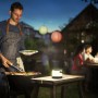 Philips Alula Solarleuchte, tragbare LED-Tischleuchte in Schwarz-Weiß, neben Grillabend im Garten.