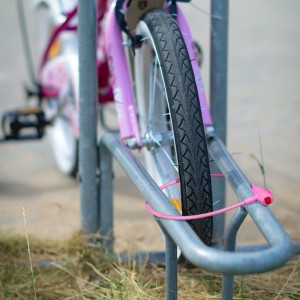 Pinkes Fahrrad mit Fahrradschloss am Fahrradständer. Kabelschloss mit Schlüssel.