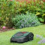 Bosch Mähroboter Indego S 500 auf Rasen vor blühendem Garten.