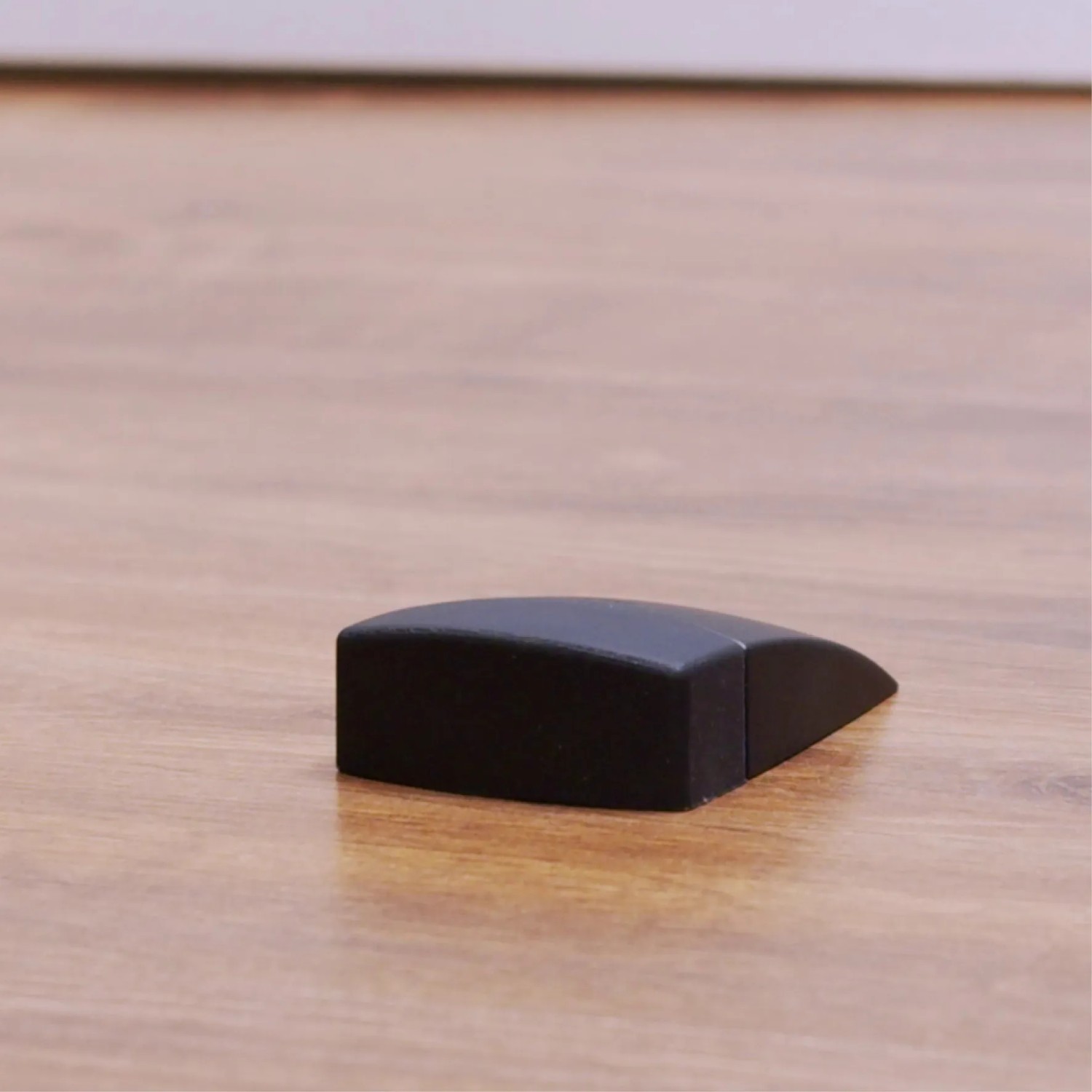 Schwarzer Wagner Bodentürstopper Black Deluxe auf Holzboden.