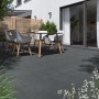 Verlegte, graue Feinsteinzeug Terrassenplatten Streetline 60x60 cm mit Sitzgruppe im Garten.