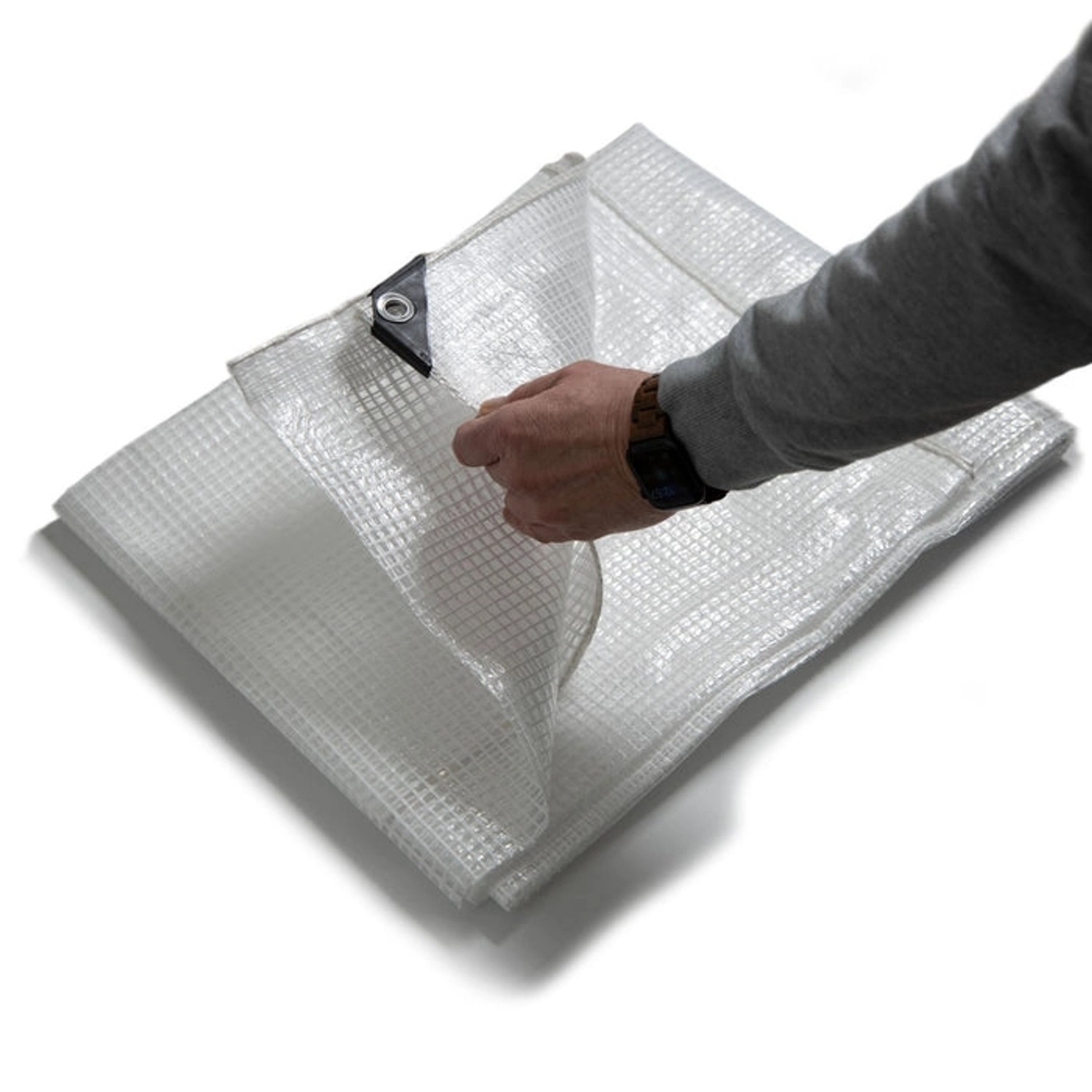 Weiße KARAT Abdeckplane (8x14m) mit Ösen, reißfest und wasserdicht. Person hält die Plane hoch.