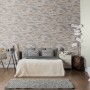Beige Vliestapete „Stones Klein“ von Erismann imitiert eine Steinwand im Schlafzimmer.