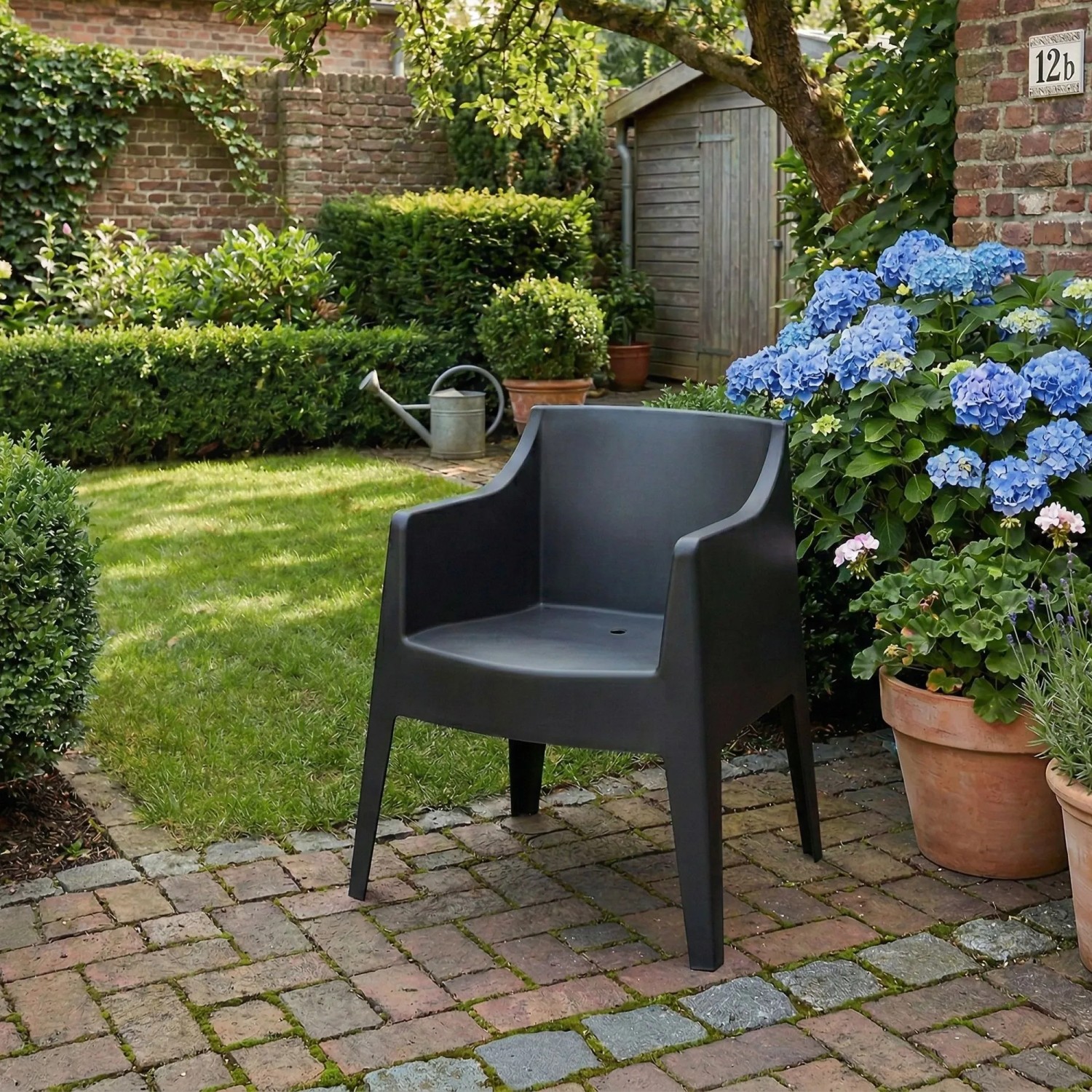 Schwarzer Kunststoff Gartenstuhl HENRI mit Armlehnen auf Terrasse. Stapelbarer Loungestuhl für Garten & Outdoor.