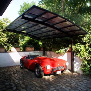 Schwarzer Ximax Alu Einzelcarport Portoforte mit rotem Oldtimer. Carport mit transparentem Dach.
