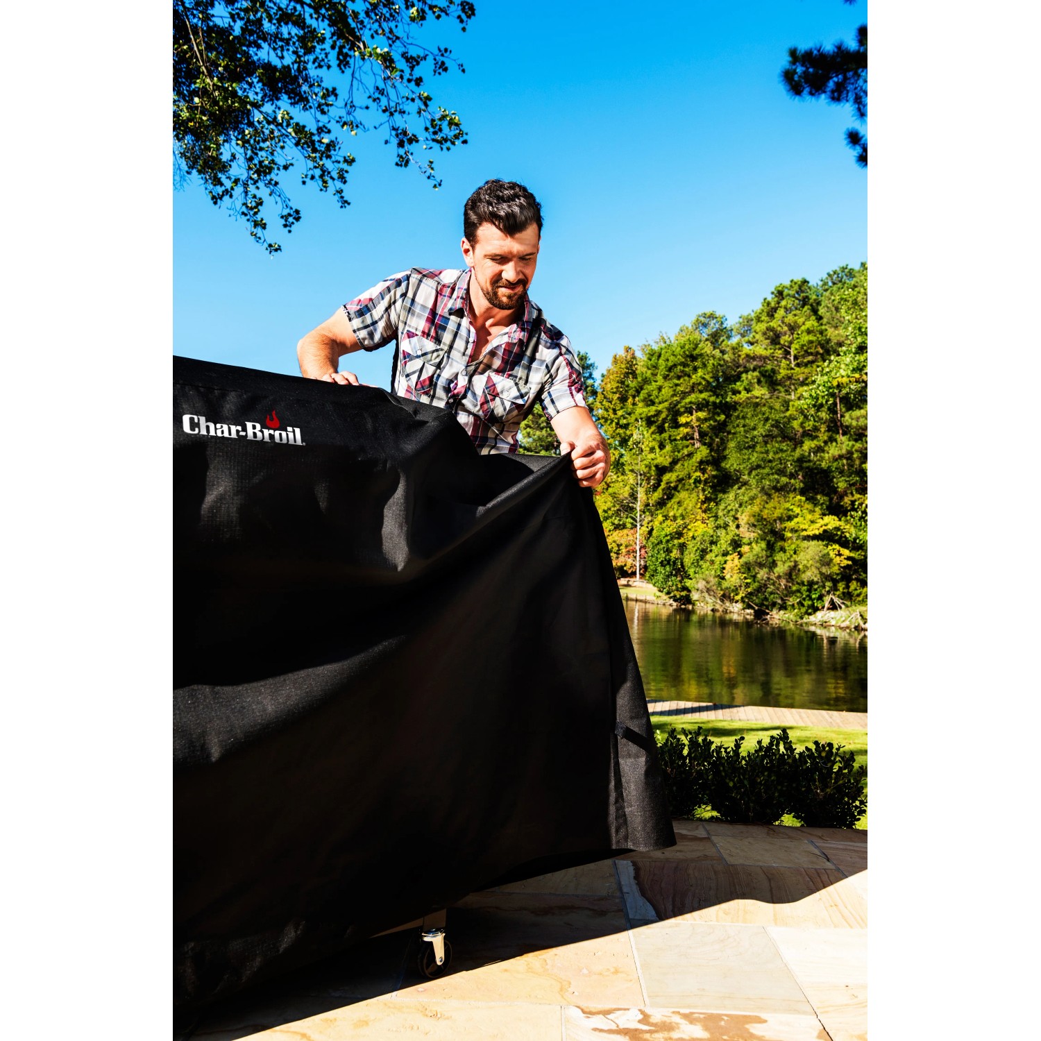 Schwarze Char-Broil Grill Wetterschutzhaube (Extra wide) wird über einen Grill gezogen.