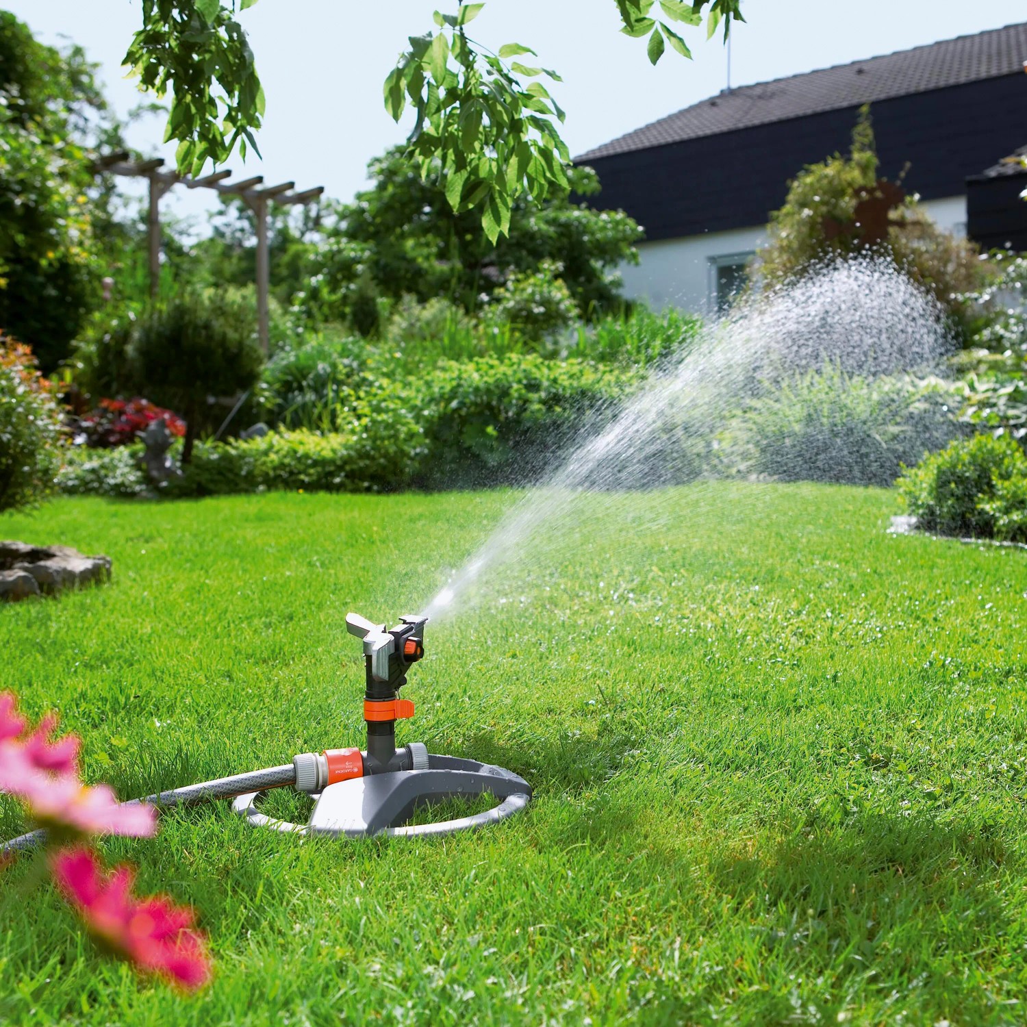 Gardena Premium Rasensprenger mit Schlitten bewässert Rasenfläche im Garten.