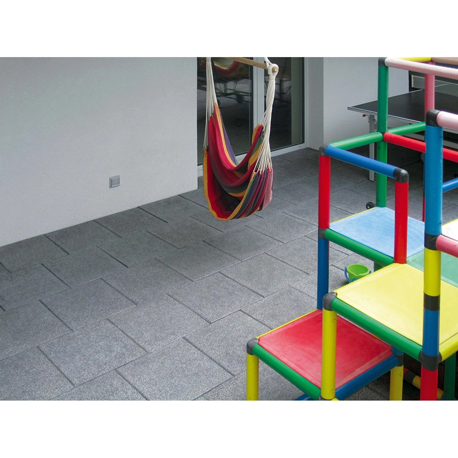 Diephaus Terrassenplatten Aguna Quarz-Anthrazit 40x40 cm auf Terrasse mit Hängematte und Spielgerüst.