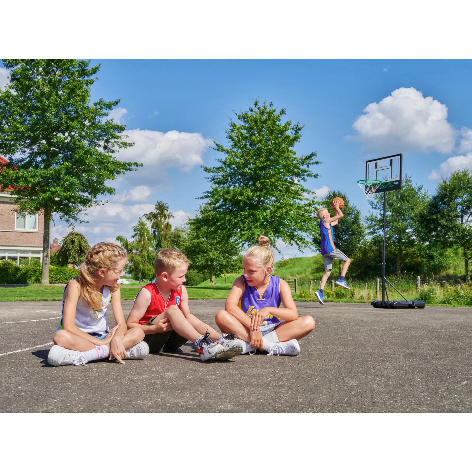 Kinder beim Basketballspielen mit dem Salta Basketballständer Dribble im Garten.