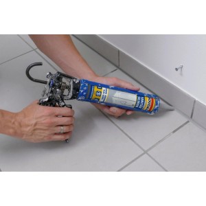 Hände dichten Fugen im Bad mit Soudal Sanitär Silikon ab. Blaue Silikonkartusche in einer Pistole.
