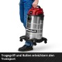 Person trägt silber-roten Einhell Nass-Trockensauger TC-VC 3055 S (30L) mit Tragegriff und Rollen.
