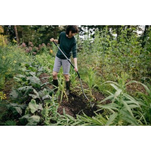 Frau arbeitet mit Fiskars Ergonomic Jäter im Garten. Besen & Rechen für die Gartenarbeit.