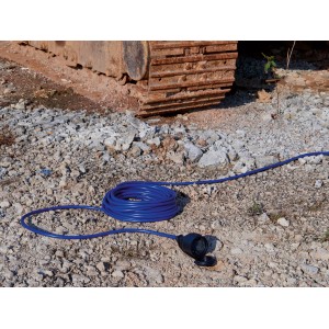 Blaues Verlängerungskabel, 10 m, IP44, auf Schotterboden, teilweise aufgerollt.