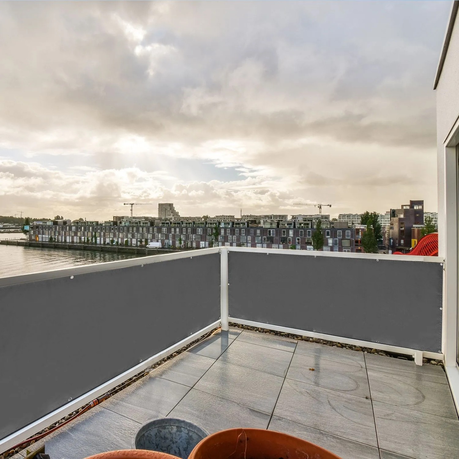 Grauer CCLIFE Balkon Sichtschutz aus Polyesterfaser, blickdicht und wetterfest, am Geländer eines Balkons mit Stadtblick.