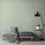 A.S. Création Vliestapete Uni Grün an Wand im Wohnraum mit Lampe und Möbeln.