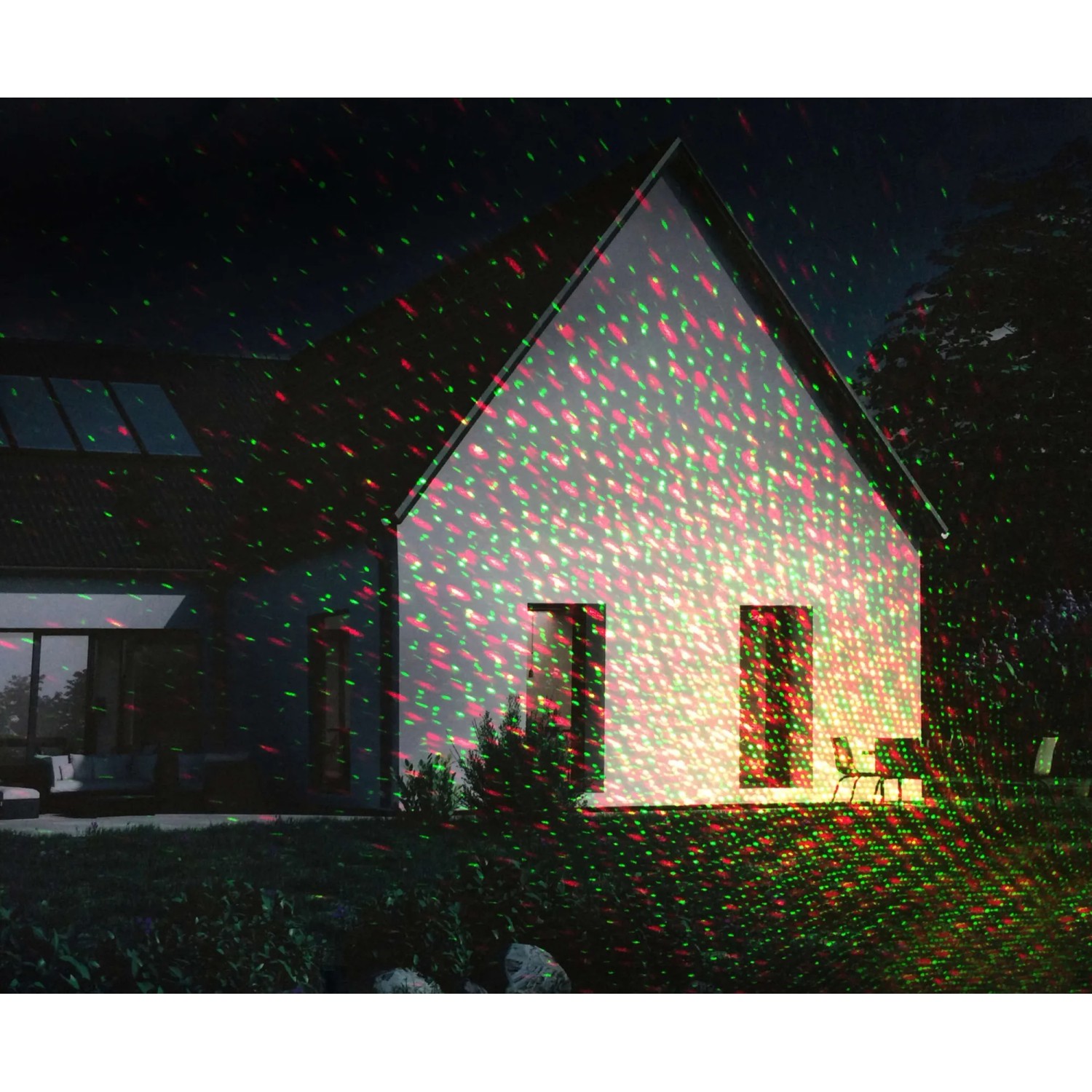 Schwarzer Näve LED Außenwandlaser Projektor projiziert rot-grüne Punkte auf ein Haus.
