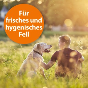 Mann streichelt Hund im Gras, orangefarbener Kreis "Für frisches und hygienisches Fell"