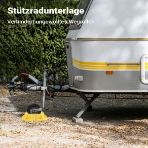 Gelbe Wiltec Stützradunterlage unter dem Stützrad eines Wohnwagens auf Schotter. Stabilisiert Anhänger, verhindert Einsinken.