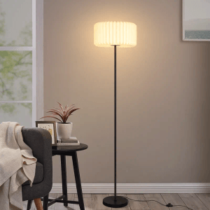 Schlanke schwarze Vintage Stehlampe mit weißem plissiertem Papierschirm, leuchtend im Wohnzimmer. Moderne Innenleuchte.