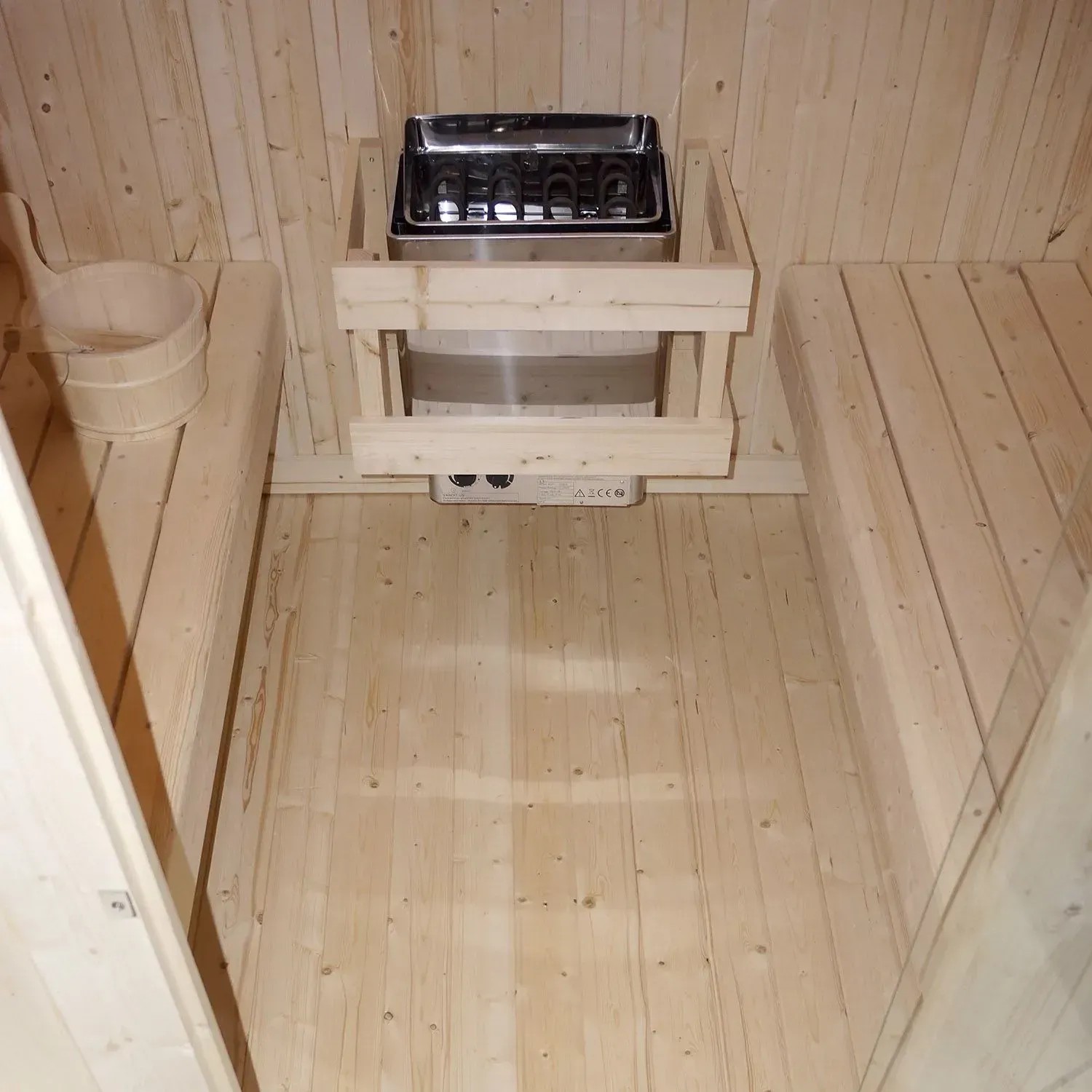 Innenansicht Artsauna Cube Fasssauna Nolvik XXL mit Saunaofen, Holzbänken und Zubehör.