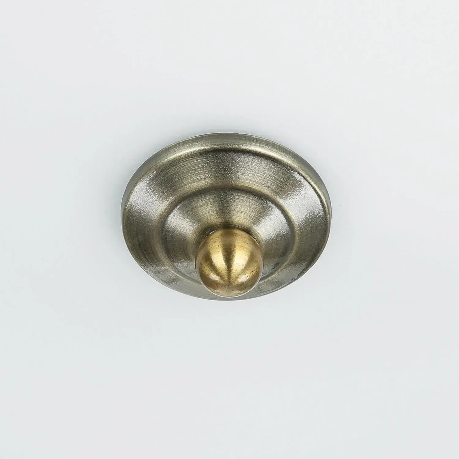 Rundes Messing-Metall-Detail in Antik-Optik mit glänzendem Messingknopf. Teil einer Deckenlampe für Badezimmer.