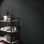 Schwarze Erismann Vliestapete Martinique Colour Passion an Wand hinter Regal.